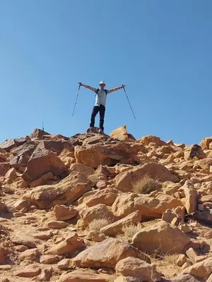 a man standing on top of a rocky mountain at Wadi Rum Sand moon Camp &Tour in Wadi Rum