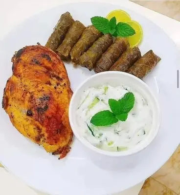 a plate of food with meat and sausages and a bowl of sauce at 77 apartment in Abū aş Şalīḩ