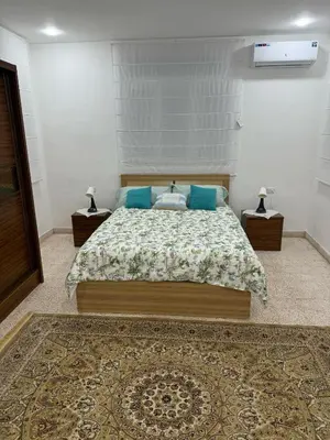 a bedroom with a large bed with blue pillows at Ahlam Apartments in Amman