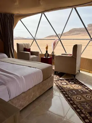 a bedroom with a bed and chairs in a tent at Whispers of Night Camp in Jurf ad Darāwīsh