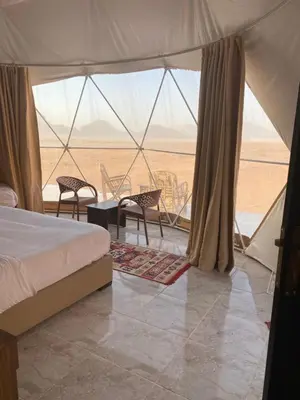 a bedroom with a bed and a table and chairs at Whispers of Night Camp in Jurf ad Darāwīsh
