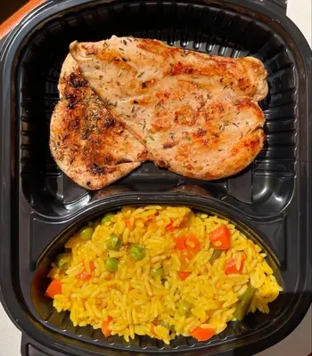 a lunch box with chicken and rice and meat at غباوي موتل in Az Zarqa