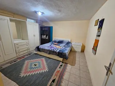 a bedroom with a bed in the corner of a room at Cozy Home with a Lovely Garden in Jurf ad Darāwīsh