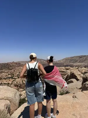 two women standing on the edge of a canyon at Dana bedouin Sky in Dana