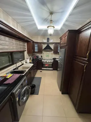 a kitchen with wooden cabinets and stainless steel appliances at Cozy 3-Bedroom Apartment in Abdoun in Amman