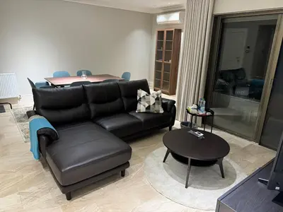 a living room with a black leather couch and a table at Cozy 3-Bedroom Apartment in Abdoun in Amman