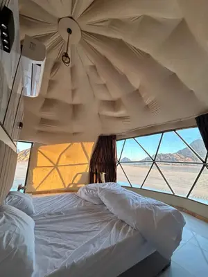 a bed in a room with a large window at Sands of time desert camp in Wadi Rum
