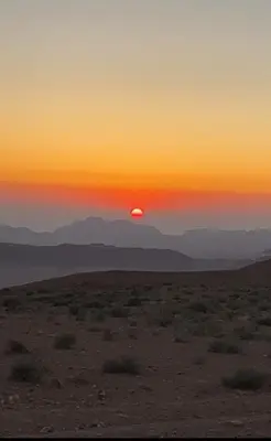 a sunset in the desert with the sun setting at Sands of time desert camp in Wadi Rum