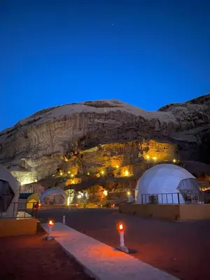 a group of tents in front of a mountain at night at في اصحراء المريخ في وادي رم in Jurf ad Darāwīsh
