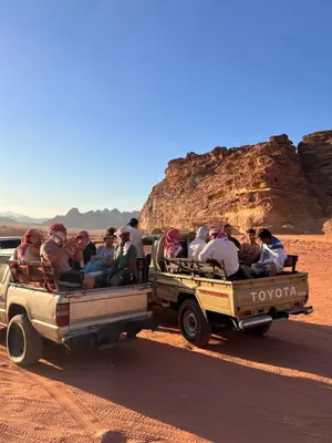 a group of people riding in the back of trucks in the desert at في اصحراء المريخ في وادي رم in Jurf ad Darāwīsh