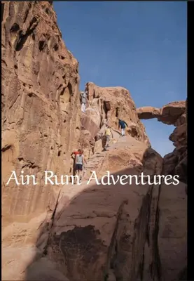 a person standing on a cliff in a canyon at مغامرات عين رم in Wadi Rum