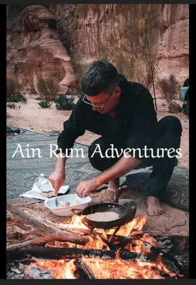 a man cooking food over a camp fire at مغامرات عين رم in Jurf ad Darāwīsh