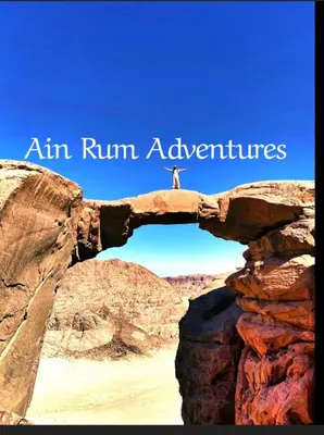 a person standing on top of an arch in the desert at مغامرات عين رم in Jurf ad Darāwīsh