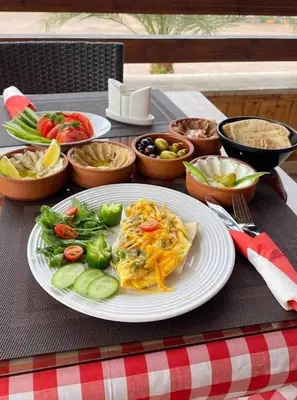a table with a plate of food on a table at Camel Dive Club By The Sea Inn in Jurf ad Darāwīsh