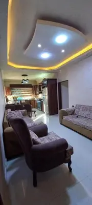 a living room with a couch and a kitchen at ام القطين لونج in Umm al Qiţţayn
