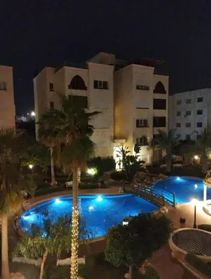 a large building with a swimming pool at night at LV luxury apartment Deir Ghbar in Amman