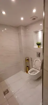 a bathroom with a white toilet in a room at LV luxury apartment Deir Ghbar in Amman