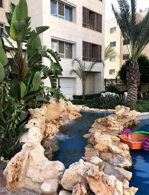 a artificial river in a yard with rocks and a building at LV luxury apartment Deir Ghbar in Amman