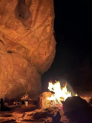 a fire in a cave with a person sitting next to it at Dana Village experience hotel in Dana