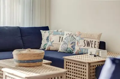a blue couch in a living room with pillows and tables at Emerald Beach Apartment in Aqaba