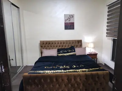 a bedroom with a large bed with a brown headboard at عمان in Jurf ad Darāwīsh