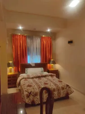 a bedroom with a bed and a window with red curtains at جرف العز هاوس in Jurf ad Darāwīsh