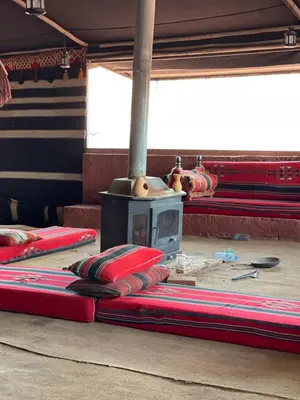 a group of red mats on the floor with a stove at Bedouin Luxury Camp in Wadi Rum