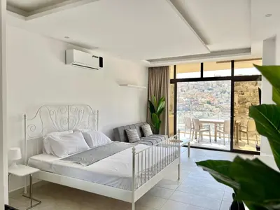 a white bedroom with a bed and a balcony at Brand new, Modern, Breathtaking view, just for you in Amman