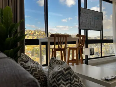a living room with a table and chairs in front of a window at Brand new, Modern, Breathtaking view, just for you in Amman