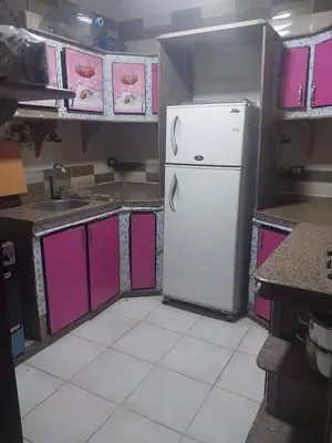 a kitchen with a white refrigerator and pink cabinets at ابيت السعاده in Ar Ramthā