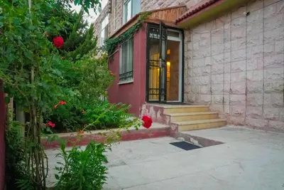 a red house with a door and some flowers at Family-Friendly Garden Stay in Jurf ad Darāwīsh