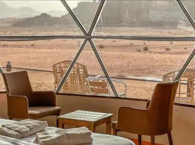 a room with chairs and tables and a view of the desert at Radisson Wadi Rum Luxury Camp in Wadi Rum