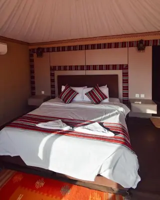 a bedroom with a large bed with white sheets and pillows at Radisson Wadi Rum Luxury Camp in Wadi Rum