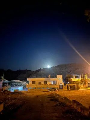 a building at night with a mountain in the background at Mohmad House in Jurf ad Darāwīsh