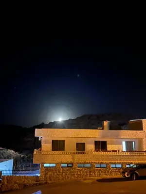 a building at night with the moon in the sky at Mohmad House in Jurf ad Darāwīsh