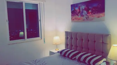 a bedroom with a bed with a pink headboard and a window at شقق ڤيڤا - viva Apartments in Amman