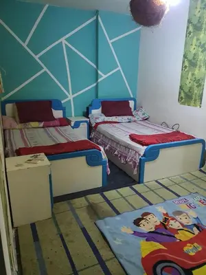 a bedroom with two beds and a blue wall at الجبل الاخضر هاوس in Al ‘Ālūk