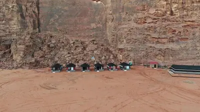 a group of chairs lined up against a rock wall at Rum bubble camp in Wadi Rum