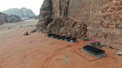 a group of trucks parked in the desert near a mountain at Rum bubble camp in Wadi Rum
