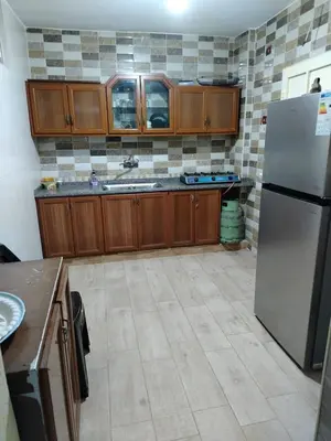 a kitchen with wooden cabinets and a stainless steel refrigerator at شقة الياسمين عمّان الأرضيّة للعائلات in Amman