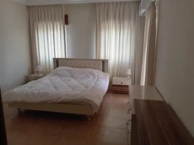 a bedroom with a bed and two windows and a table at Stay with Saja Homey Room Heart of Weibdeh in Jurf ad Darāwīsh