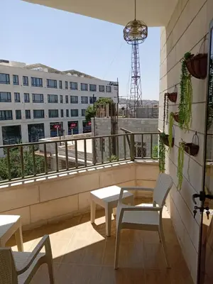 a balcony with a table and chairs and a building at Stay with Saja Homey Room Heart of Weibdeh in Jurf ad Darāwīsh