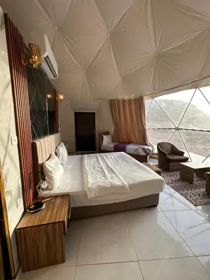 a bedroom with a bed and a large window at RUM FLORAA LUXURY CAMp in Wadi Rum