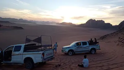 a group of people standing around a truck in the desert at Wasan Camp Wadi Rum in Wadi Rum