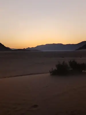 a sunset in the desert with mountains in the background at Wasan Camp Wadi Rum in Wadi Rum