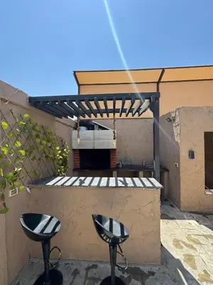 two stools sitting on a patio with a pergola at Oia chalet in Ash Shāghūr