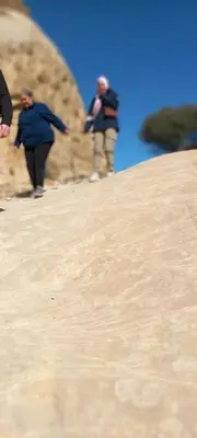 a group of people walking up a sand hill at Camping in Dana in At-Tafilah