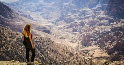 a woman standing on top of a mountain overlooking a valley at Camping in Dana in At-Tafilah