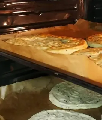 a group of pizzas are cooking in an oven at ايدون هاوس in Aydūn