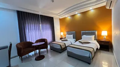 a hotel room with two beds and a chair at Tetra Tree Hotel 1 in Wadi Musa